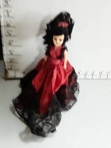 lot 2005 image: Small doll in red and black dress. Black lace needs to be sewn back on