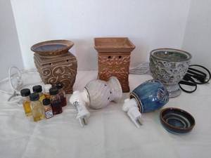 lot 2040 image: 3 wax warmers- one without tray(is a scentsy), 2 plug- in wax warmers and assorted warming oils
