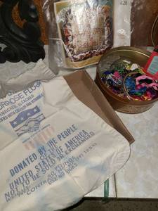 lot 2212 image: Cross stitch kit, tin of embroidery thread and hoops and old flour bag