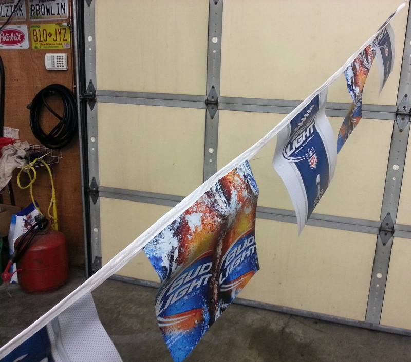 lot 9181 image: Over 30 ft long string of Bud Light sponsored NFL Super Bowl XLVI plastic flags.