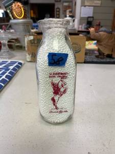 lot 58 image: Glass milk bottle, Coleman milk Annie Oakley red writing.
