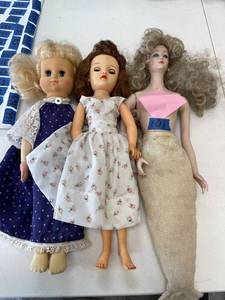 lot 101 image: doll lot- Porcelain mermaid doll (no top) unmarked, hard rubber ideal doll in floral dress with brunette hair, unmarked cloth and rubber blonde hair doll.
