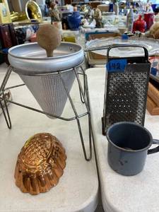 lot 142 image: Vintage colander with wood masher, copper pineapple jello mold, grater, granite ware mug.