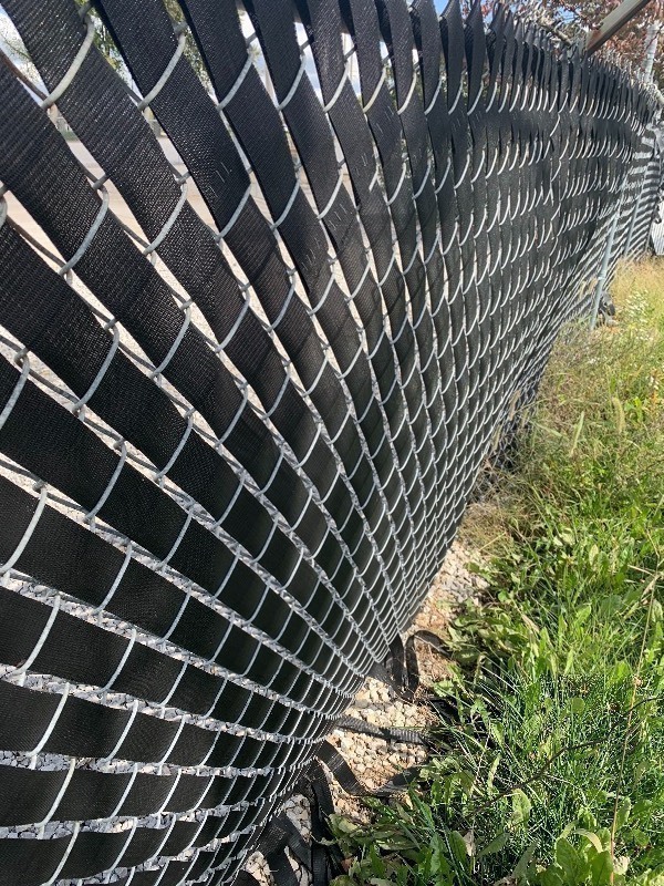lot 950 image: Two rolls of vinyl webbing 100 yards each dress up your chain link fence as pictured