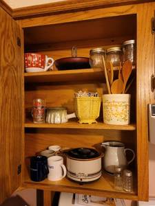 lot 346 image: Contents of Kitchen Cabinet (Pottery, Salt and Pepper Shakers, Mini Crockpot, Wooden Utensils, Matches, Jelly Jars, Stoneware, Nut Dish, Coffee Cups) BRING YOUR OWN BOXES
