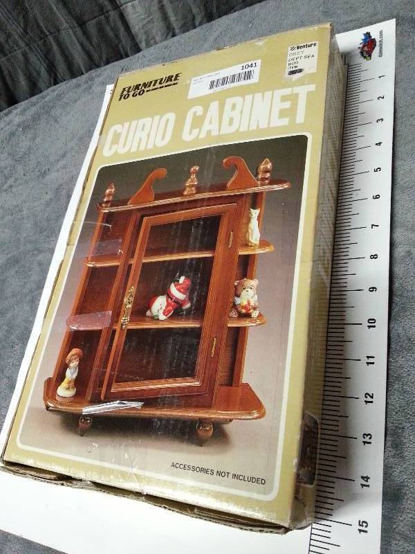lot 1042 image: New in the package is this cute small wooden curio cabinet with assembly instructions.