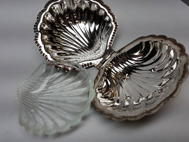 lot 8498 image: About 4 wide is this hinged clam shell silver plated jewelry case with glass inner liner.