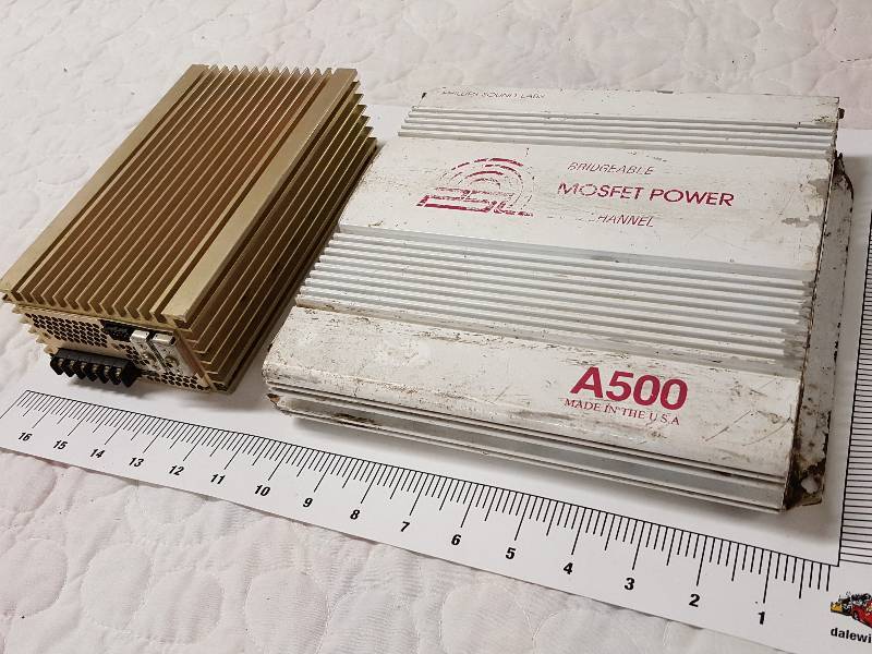 lot 1125 image: Pair of in the trunk amplifiers.  One looks like it was rode hard and put away wet but he said it was working when he wrecked the car.