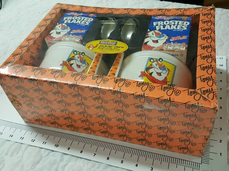 lot 1128 image: New in the package is this Kelloggs Frosted Flakes Gift pack for kids including 2 quality bowls, spoons and a small box of cereal