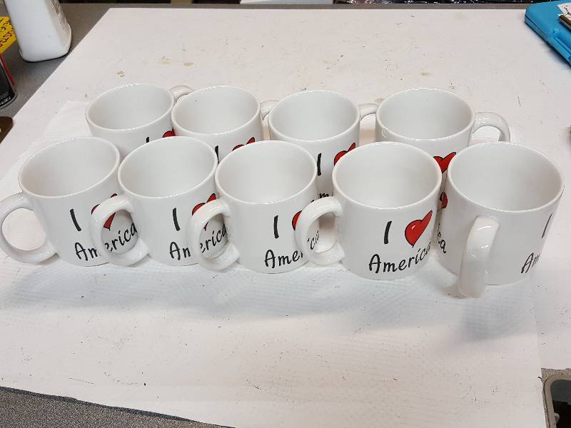 lot 8356 image: 9 nice looking I Love America coffee cups.  New, but bid like a couple have chips in them cause a couple do