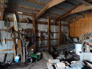 lot 11112 image: Variety of Auto Parts - Tools - Canvas Tarp & Misc  Contents in SW Corner of Barn  Metal Shelf and Barrel w Contents  Items on Wall and Floor  East 12 of West Barn
