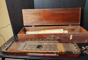 lot 117 image: Antique Ukelin (Over 150 Years Old) by International Musical Corporation with Sheet Music, Tuning Key, and Handmade Wooden Case (located in basement)