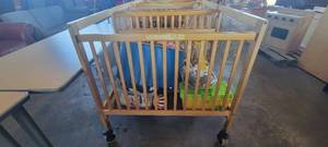 lot 39847 image: Wooden Whitney Evacuation Crib W Assorted Toys and Books