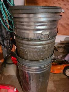 lot 4034 image: Four 30 gal. metal trash cans and lids. The bottom one has holes drilled for composting.