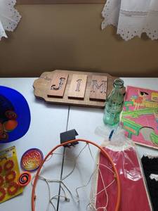 lot 2060 image: Crate with wooden sign, leg pads for softball, variety of small hand toys, Coca-Cola bottle, stuffed bear, crocheted slippers tennis shoes, KC ball helmet