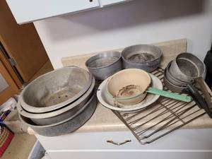 lot 4301 image: Aluminum and enamelware bowls and pots used in the yard. Several have holes in the bottom. Two oven racks.