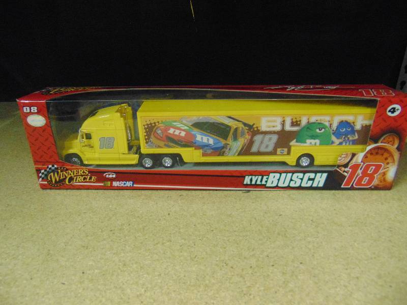 lot 4022 image: Kyle Bush #18 M&Ms Racing Nascar 164 scale transporter and die-cast car, Winners circle