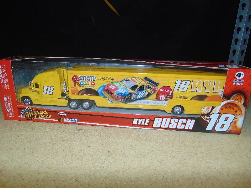 lot 4023 image: Kyle Bush #18 M&Ms Racing Nascar 164 scale transporter and die-cast car, Winners circle