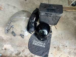 lot 1197 image: Bundle of Motorcycle Attachments - Harley Davidson Windshield, Daytona Helmet, Harley Side Pouch, and Unbranded Leather Saddle Bag
