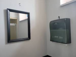 lot 15593 image: Contents of Bathroom- Small Black Wooden Framed Mirror, Oasis Creations Towel Dispenser, and a Black Trash Bin