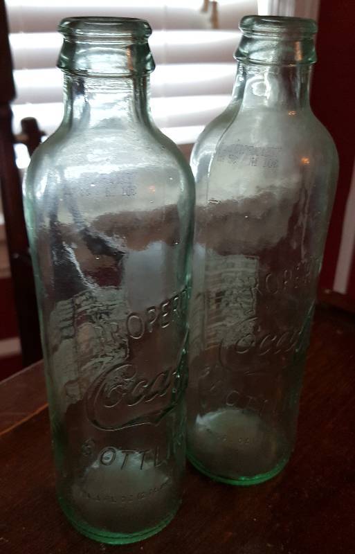 lot 6622 image: A couple of empty CocaCola glass bottles that are the same bottles as the 125 year anniversary 4 packs