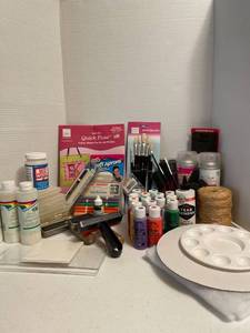 lot 1165 image: Tub of craft supplies, paint brushes, twine, fabric markers, craft aprons, and 16 bottles of unopened craft paint