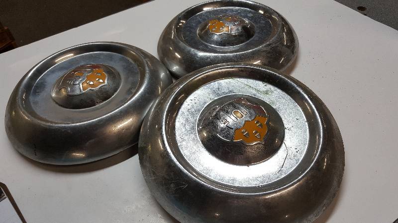 lot 6407 image: Dont recognize this log on these 3 heavy hub caps.  Make a clock or trophy out of these hub caps