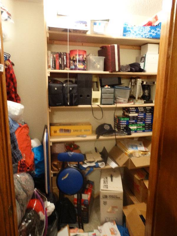 lot 964 image: Contents of Closet - VHS Tapes, New Door Knobs, Lock boxes (2) w no keys, Pillows, Comforters, Hats, Bags, Clothes & Hangers, Plastic storage tubs, & misc.