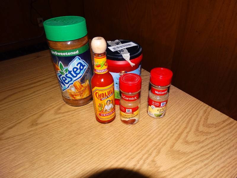 lot 620 image: Ground cinnamon & celery salt spices, Cholula hot sauce, 25% left unsweetened nestea, 12 a bag of powdered sugar.
