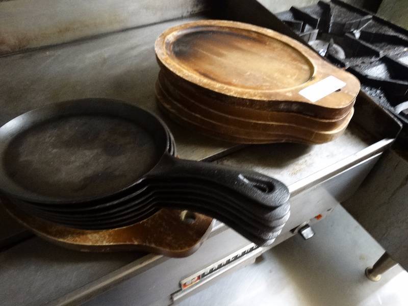 lot 745 image: 6 iron individual entree skillets with wood under plates.