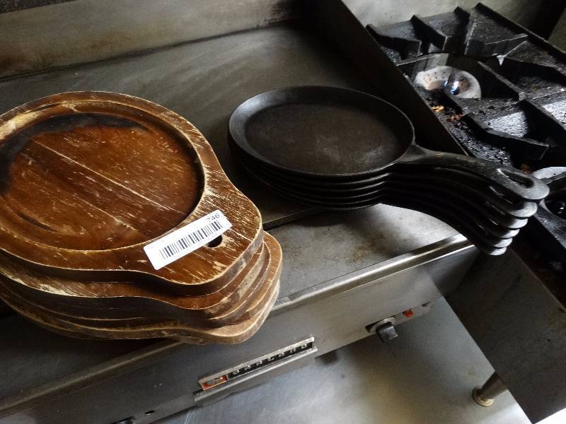 lot 746 image: 6 iron individual entree skillets with wood under plates.