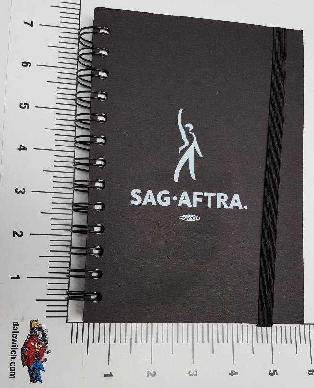 lot 6645 image: Its new and has an elastic band to keep it closed.  A whole bunch of lightly ruled all blank pages with spiral binding.