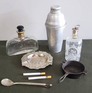 lot 84 image: Antique Soda Spoon from The Washington-Youree Hotel in Shreveport, LA, Old Cocktail Shaker, Cast Iron Automotive Parts Co., Inc Frying Pan Ashtray & Cigarette Lighters, Etched Cordial Bottle & Gold Trim Decanter with Onyx Glass Stopper, KANSAS Ashtray