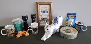 lot 85 image: For the CAT LOVER - Large Porcelain Transfer Cat Figurine 14in L x 7in T, Framed Print, Coffee Mugs, Bobble Head NIP, Vintage Avon TABATHA Black Cat Cologne Bottles, Carved Wood Calendar Cat, & Chocolates Tin