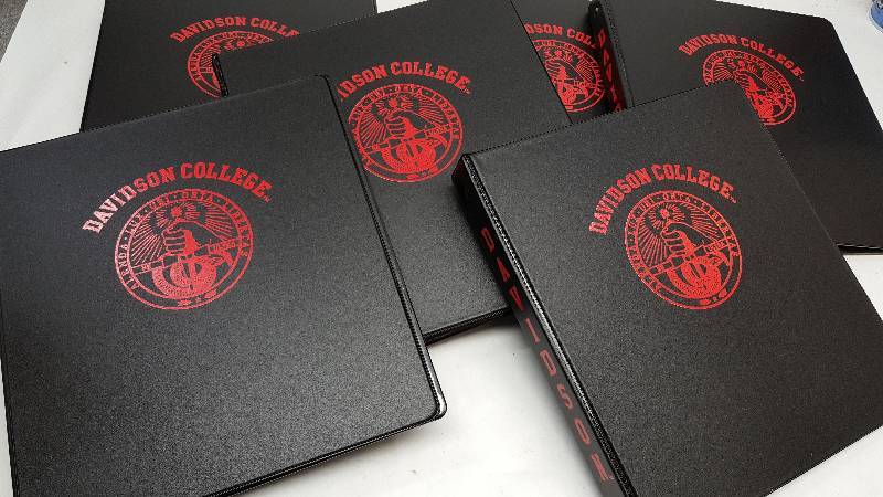 lot 5278 image: 6 new standard size 3 ring note book binders with the Davidson College logo screened on the front.