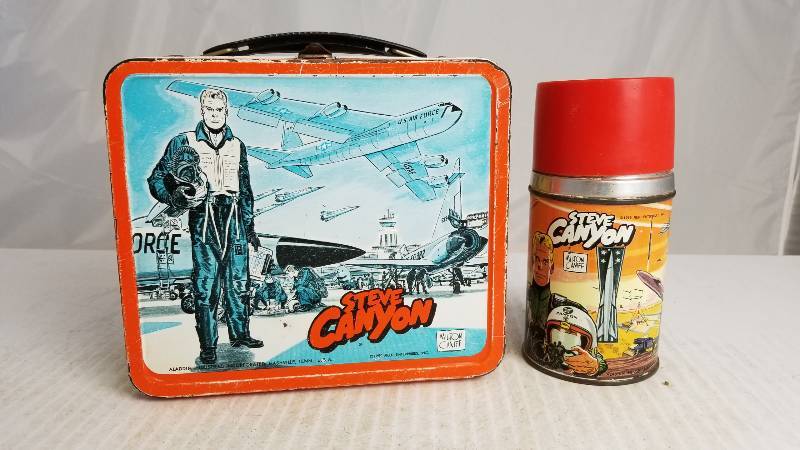 lot 3898 image: 1959 Steve Canyon W Aladden Glass Lined Thermos Vintage Metal Lunch Box