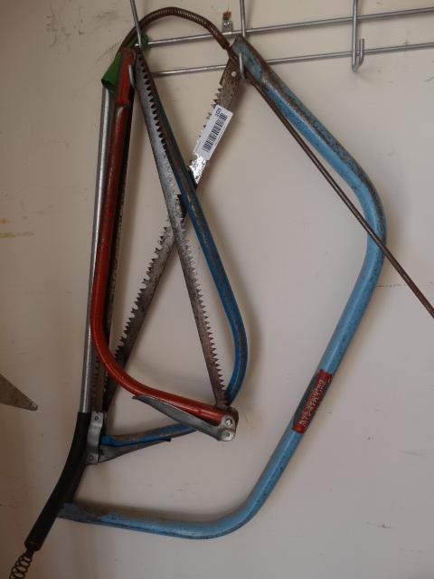 lot 105 image: 3 Hand Saws & Sewer Snake - on wall rack.