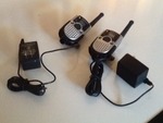 Two small walkie-talkies both with chargers