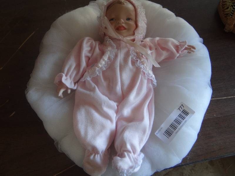 lot 777 image: Porcelain baby doll in pillow.