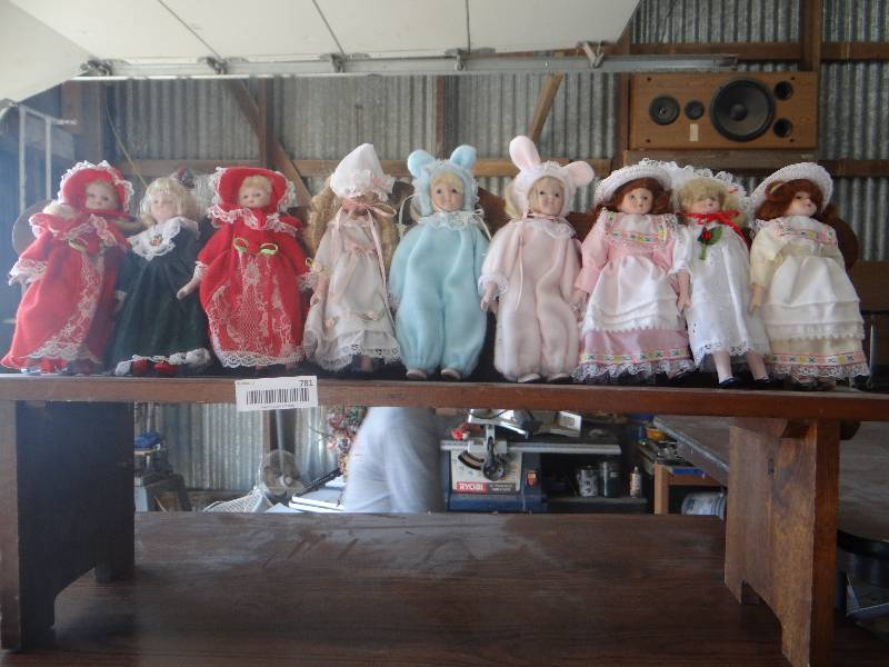 lot 781 image: Lot of small porcelain dolls on wood bench.