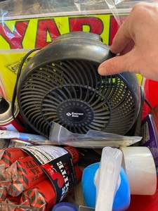 lot 2669 image: Garage basket- yard sale signs, fan, spray paint, battery cleaner, hot sauce that looks like fireworks, etc