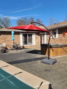 lot 910 image: Offset Patio Umbrella with Stand - 10ft Red Cantilever- Base Loaded with Sandbags