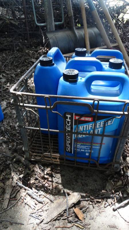 lot 1823 image: 3- New 1- Gallon antifreeze and 1 half empty with metal crate.