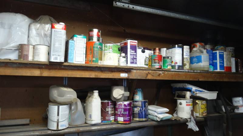 lot 1857 image: Shelf contents, paint thiner, camp fuel, paints, 2 bread makers, etc.