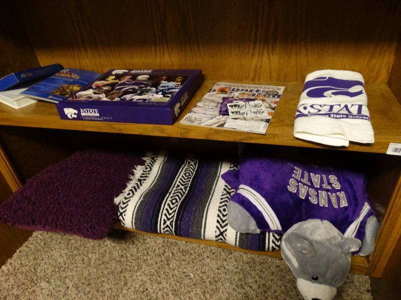 lot 267 image: 2 shelves of K-State. Pillows, blankets, magazine and buisness cards with signatures