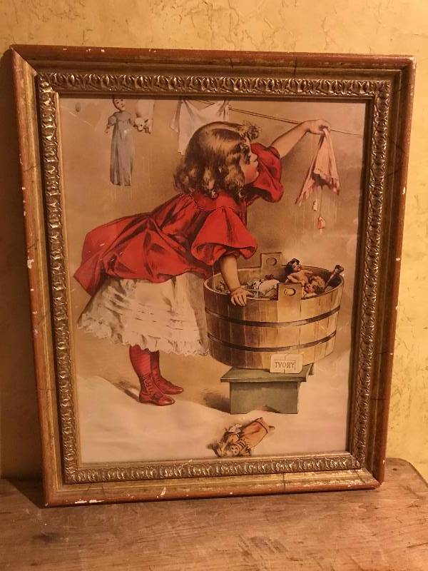 lot 14 image: Framed Wall Art of girl doing laundry.   Titled A Busy Day featuring Ivory Soap Girl