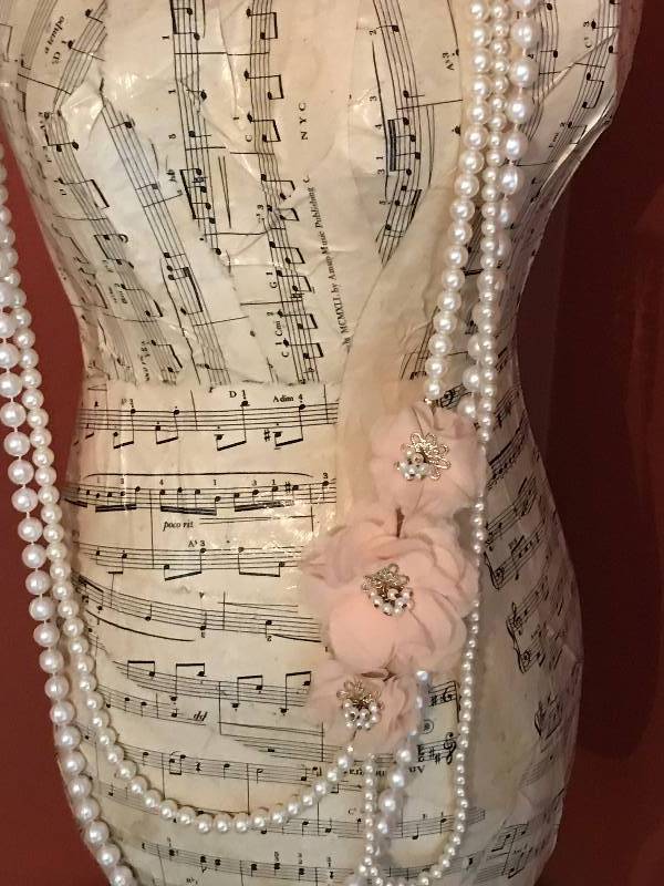 lot 1117 image: 26 12  dress dummy covered in musical sheets and pearl bead necklaces