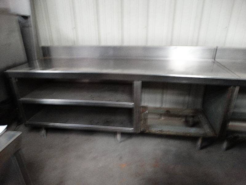lot 2537 image: 7L x 28D Stainless steel table. Holes on left and pegs on right for securing joining tables or equipment.