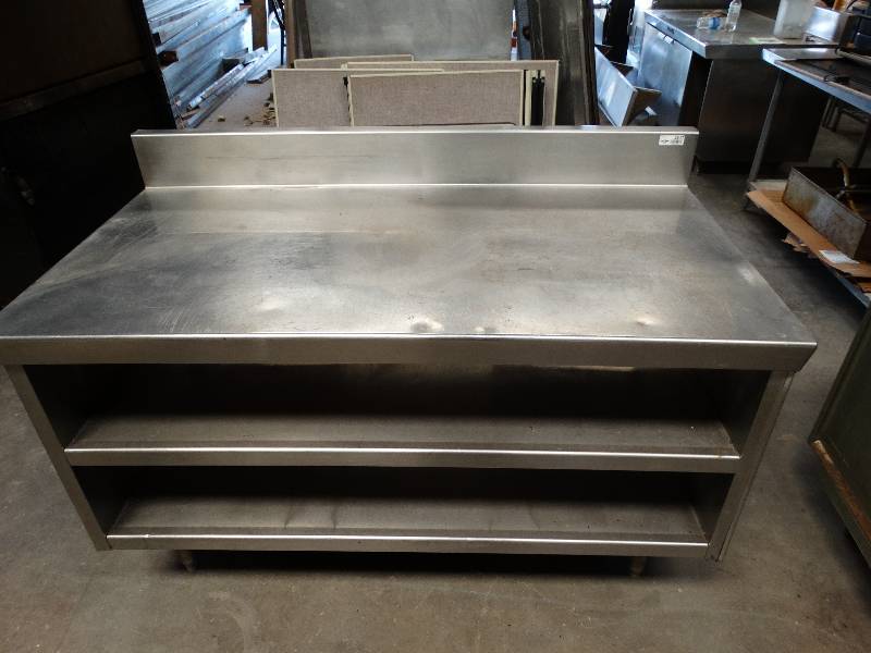 lot 2547 image: Stainless steel table with backsplash and 2 lower shelves. Holes on the left side for securing another table or equipment.