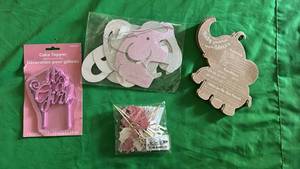 lot 546 image: Baby Girl Shower items, Elephant Banner that Says Baby Girl, 30 Pc Elephant Baby Predictions and Advice, Its A Girl Cake Topper, and Pink Cake and Cupcake Toppers in a Complete Bag.